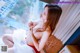 A woman in a red lingerie sitting on a window sill.