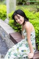 A woman in a white dress sitting on a wooden bench.