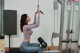 A woman is doing a pull up on a gym machine.