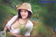 A woman in a straw hat sitting on a pile of hay.