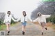 A group of young women walking down a dirt road holding hands.