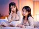 A couple of women laying on top of a bed.