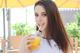 A woman holding a glass of orange juice with a straw.